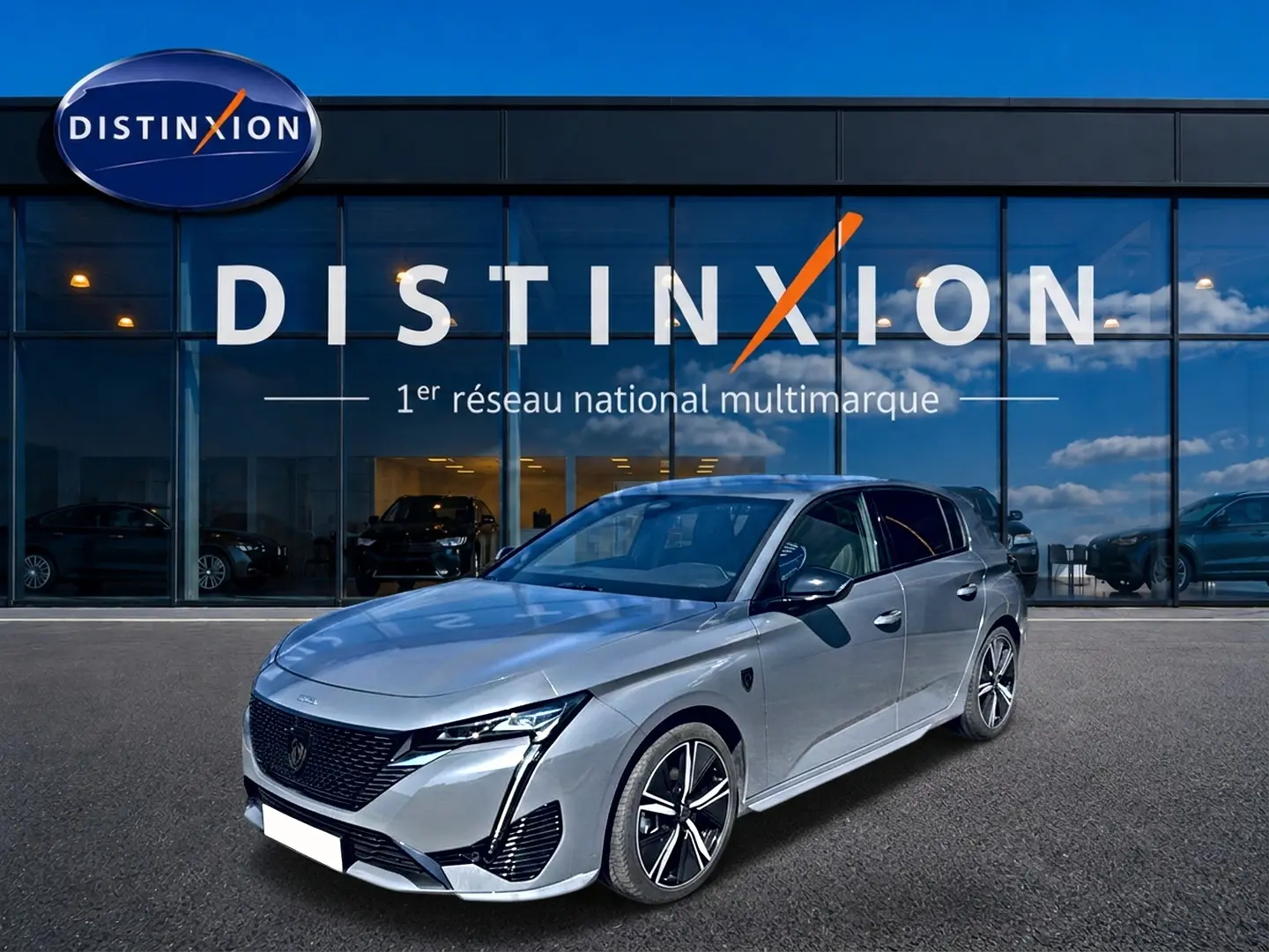 Peugeot 308 1.2 hybrid gris vue 3/4 avant droit, avec jantes alu et calandre noire distinctive.