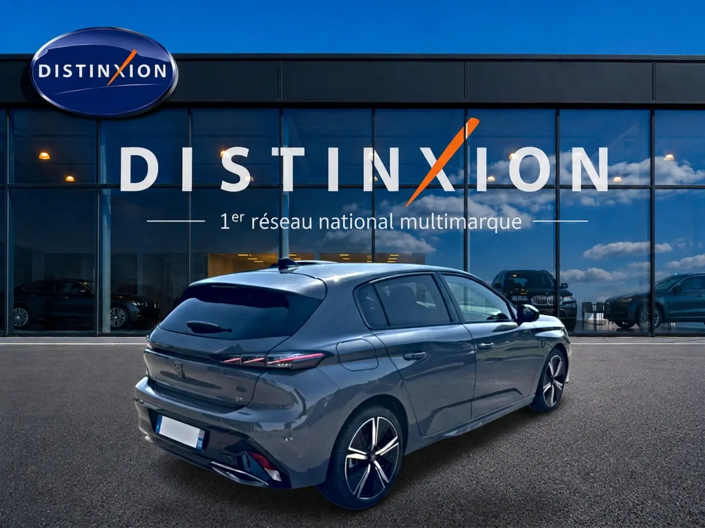 Vue 3/4 arrière droite d'une Peugeot 308 gris métallisé avec jantes alliage, devant une vitrine Distinxion.