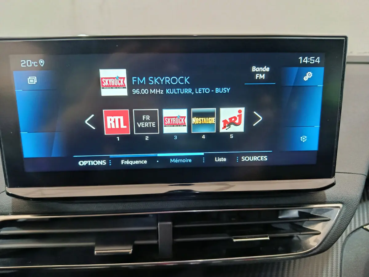 Écran tactile central du tableau de bord du Peugeot 3008 bleu, affichant les stations radio FM avec interface moderne.