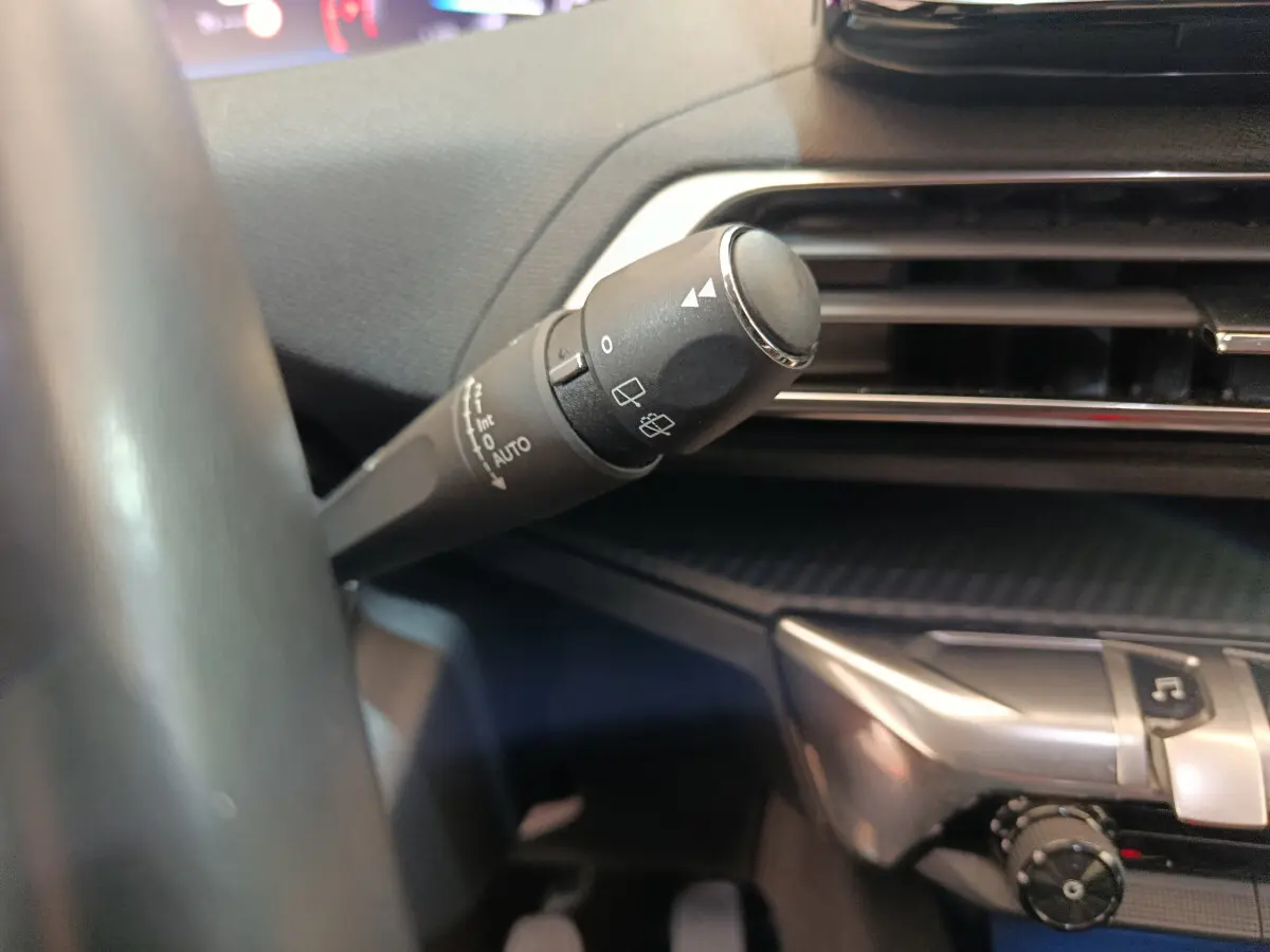 Gros plan sur la commande d'essuie-glace à gauche du volant dans l'habitacle du Peugeot 3008 bleu PureTech 2022.