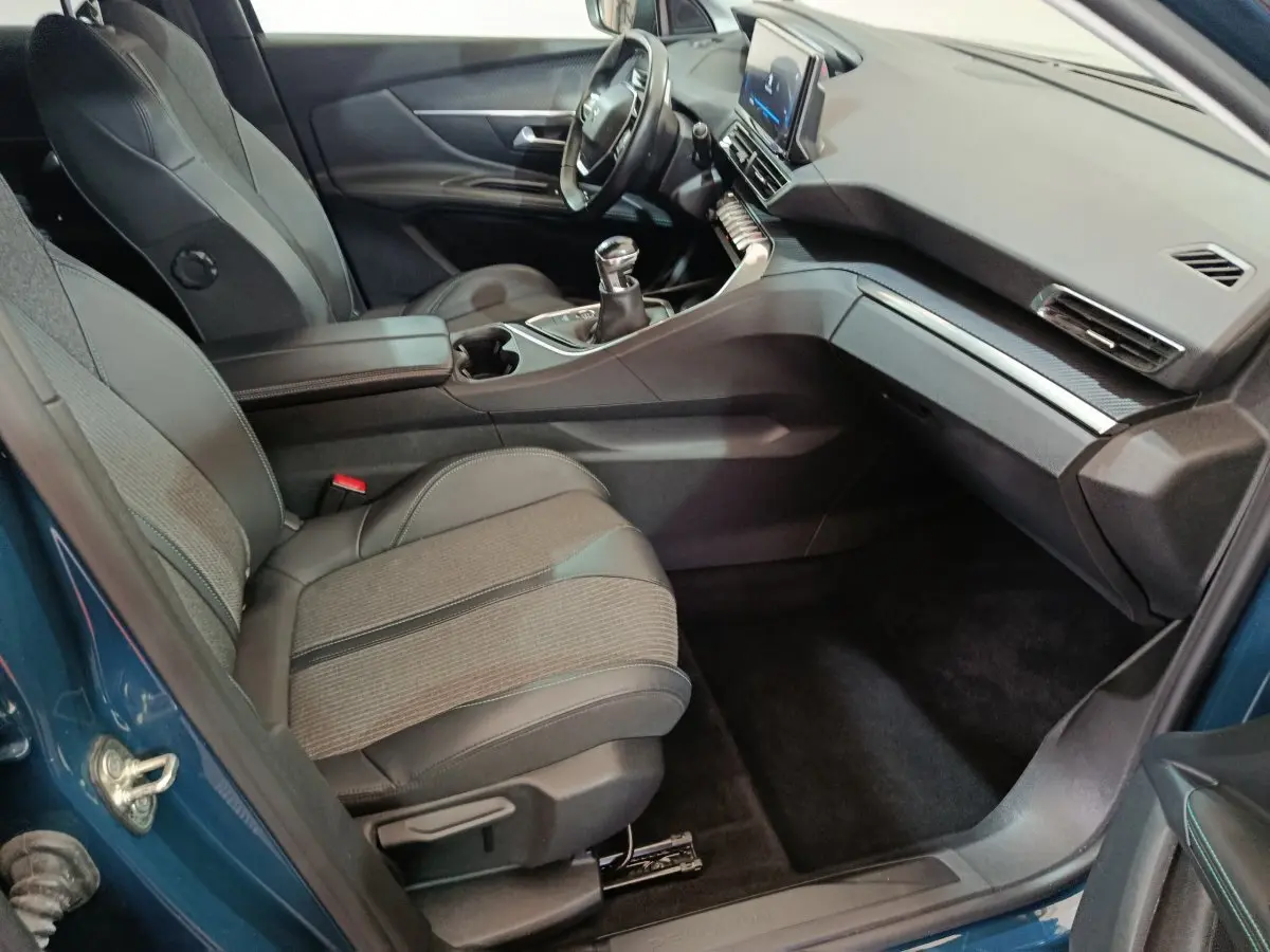 Intérieur avant droit du Peugeot 3008 bleu 2022, sièges tissu-cuir et tableau de bord avec écran tactile central.