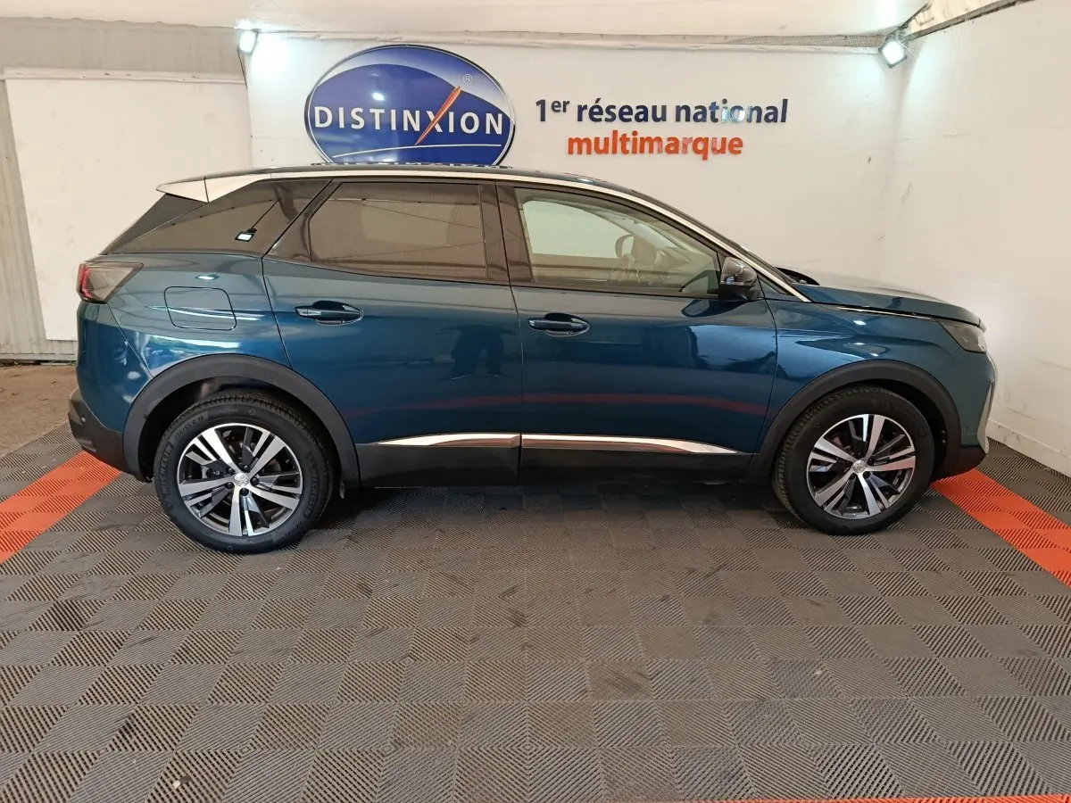 Profil côté gauche d'un Peugeot 3008 bleu 2022 garé en intérieur avec jantes alliage et vitres teintées.
