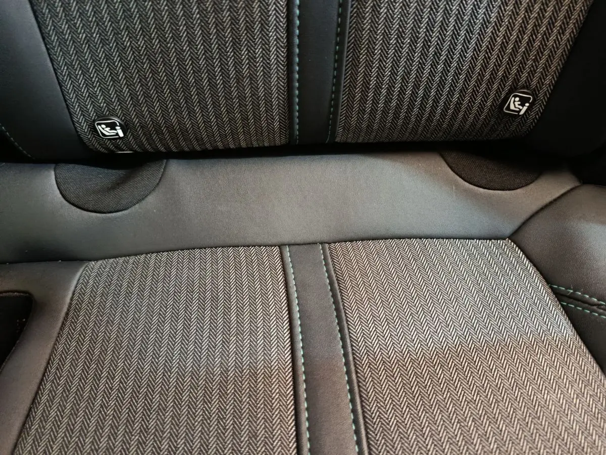 Gros plan sur la banquette arrière du Peugeot 3008 2022, tissu gris à motif chevrons avec coutures vertes et logos Isofix.