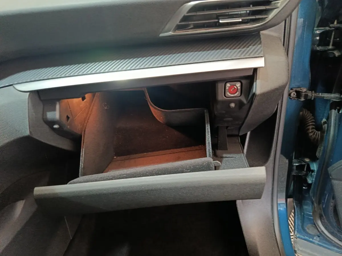 Vue intérieure côté passager du coffre à gants ouvert du Peugeot 3008 bleu 2022 avec éclairage intérieur.