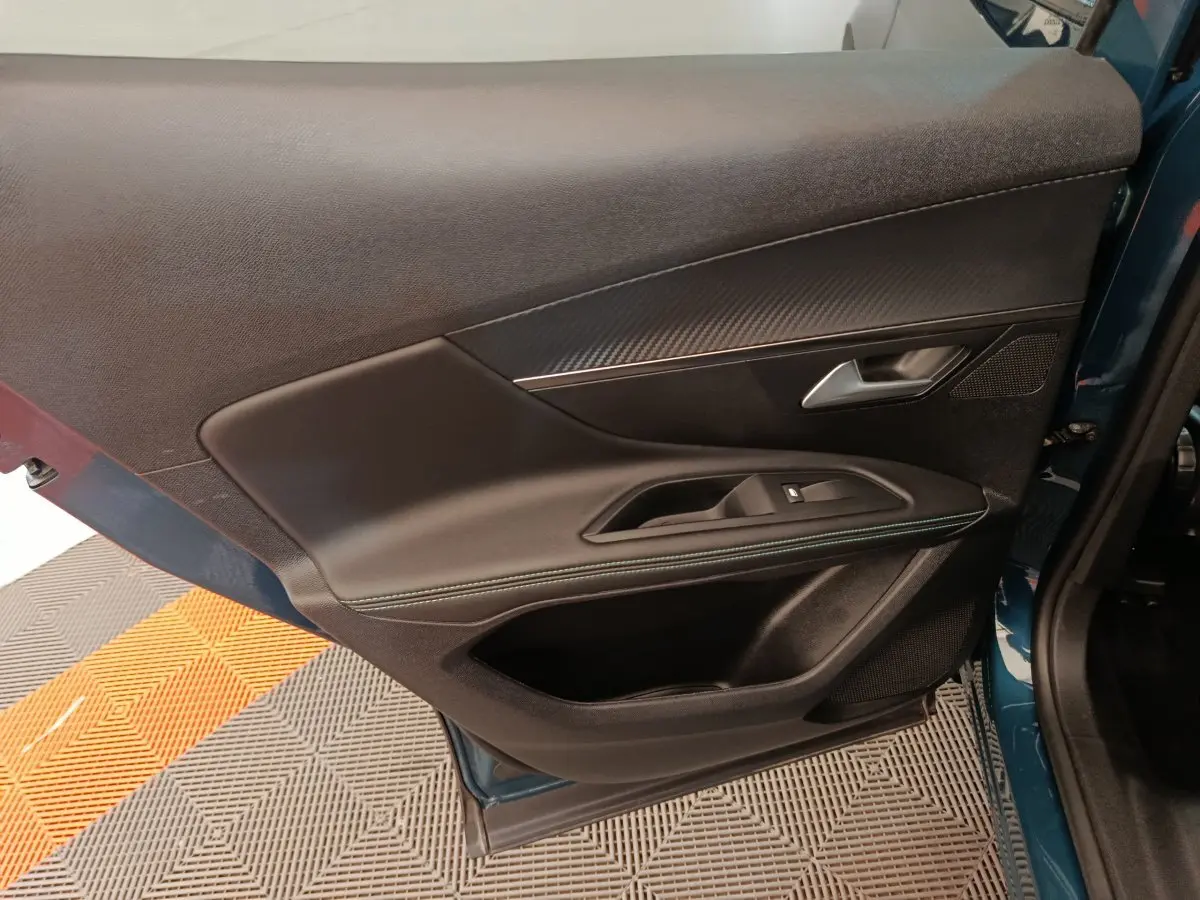 Porte avant gauche ouverte du Peugeot 3008 bleu 2022, montrant garniture noire avec surpiqûres et poignée argentée.