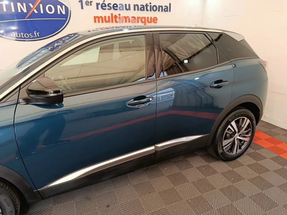 Profil côté gauche du Peugeot 3008 bleu 2022 avec jantes alliage et toit noir contrasté visible en intérieur showroom.