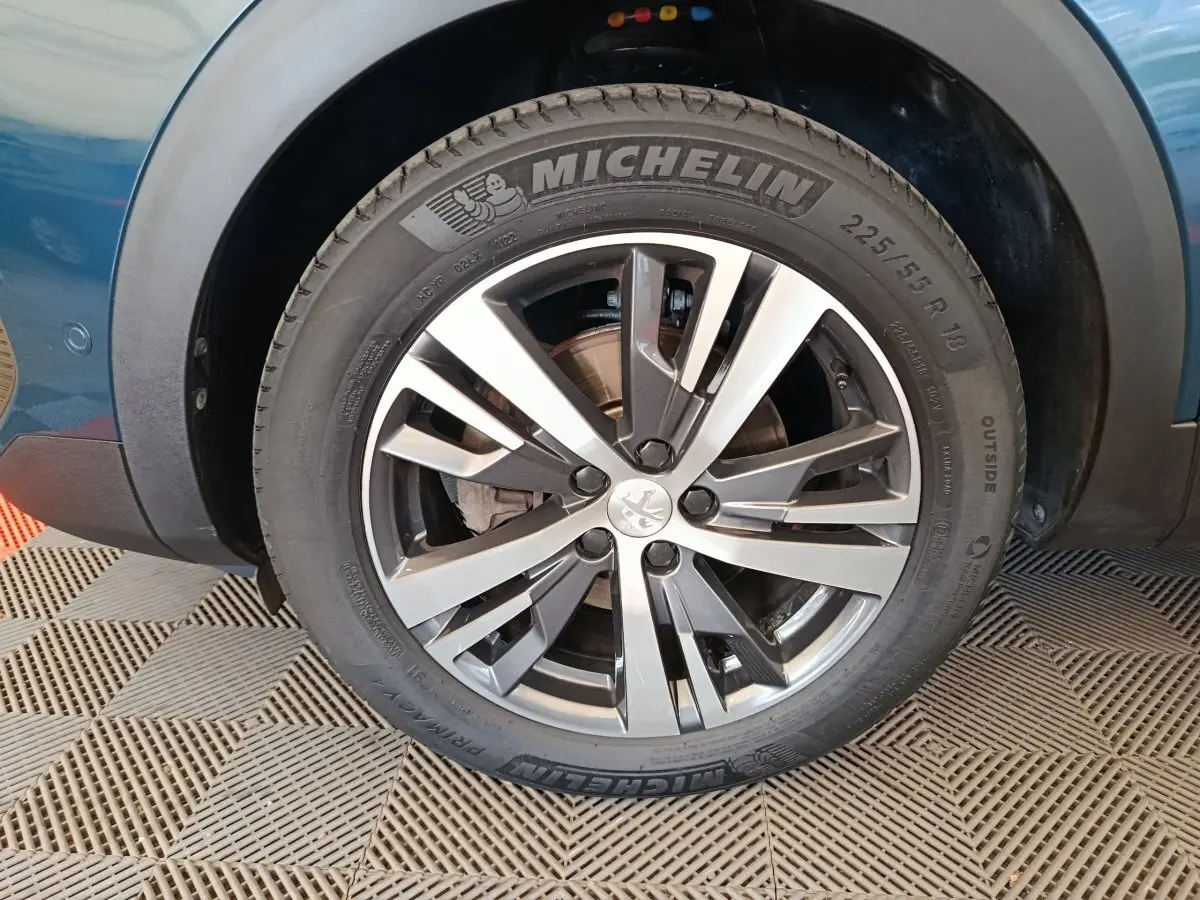 Gros plan sur la roue avant gauche du Peugeot 3008 bleu 2022 avec jante alliage et pneu Michelin visible.