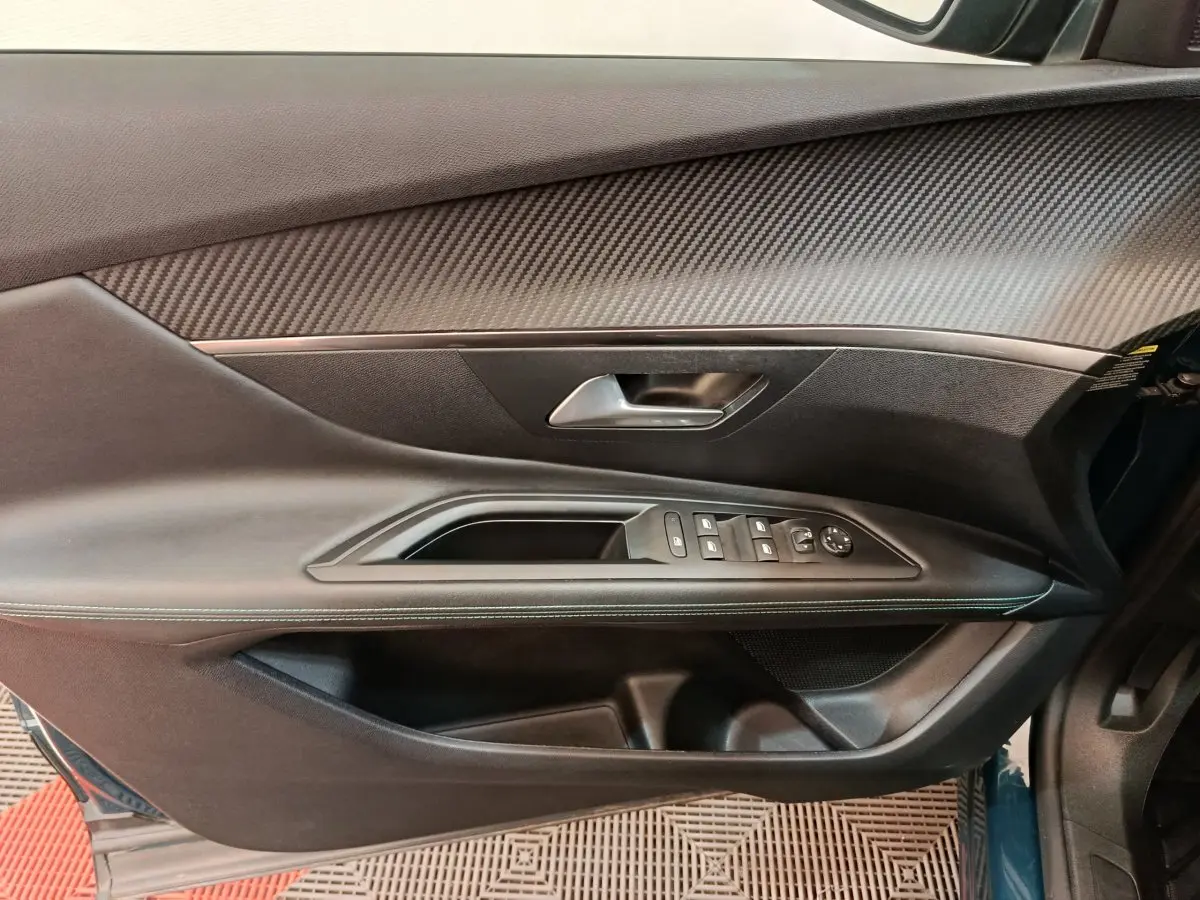 Porte côté gauche du Peugeot 3008 bleu, vue intérieure montrant les commandes des vitres et le revêtement texturé.