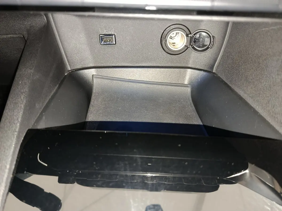 Gros plan sur la console centrale noire du Peugeot 3008 bleu, avec prise USB et allume-cigare visibles.