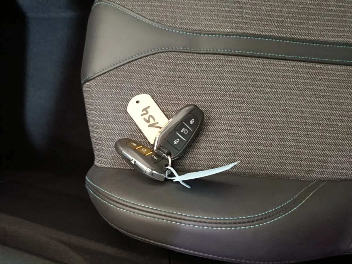 Gros plan sur les clés posées sur la sellerie noire et grise avec surpiqûres bleues du siège avant d'un Peugeot 3008 bleu.
