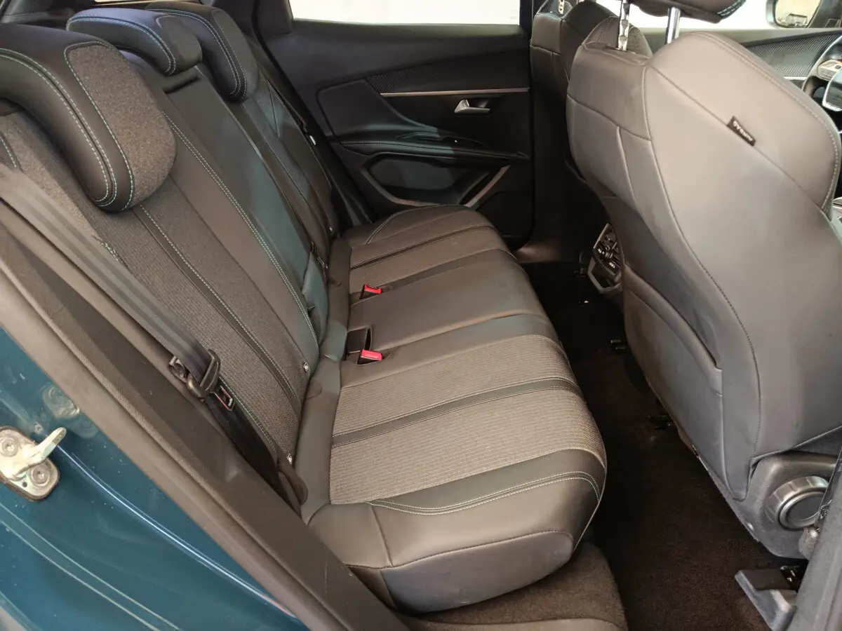 Vue côté gauche sur la banquette arrière en tissu et cuir du Peugeot 3008 bleu, avec appuie-têtes et ceintures visibles.