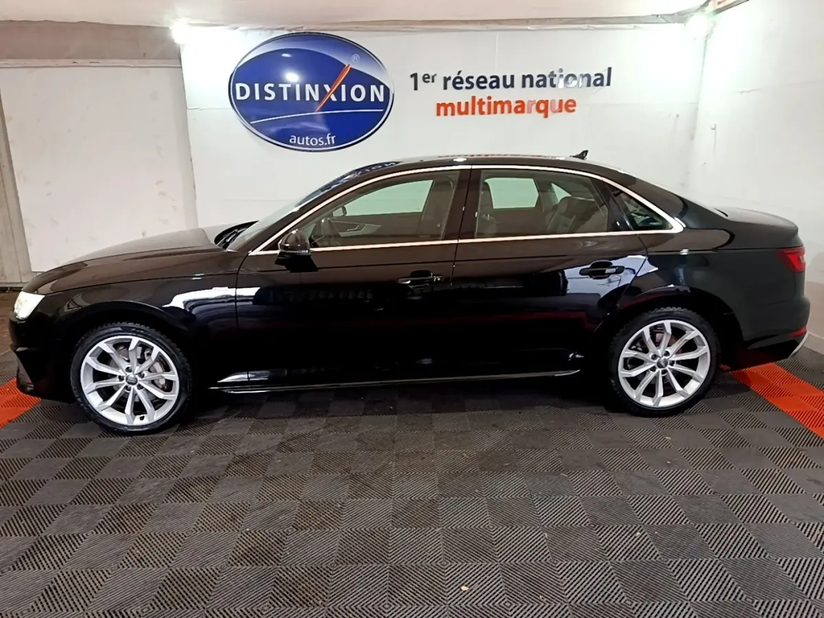 Profil côté gauche d'une Audi A4 noire 2018 Design Luxe, avec jantes alliage et vitres teintées en intérieur showroom.