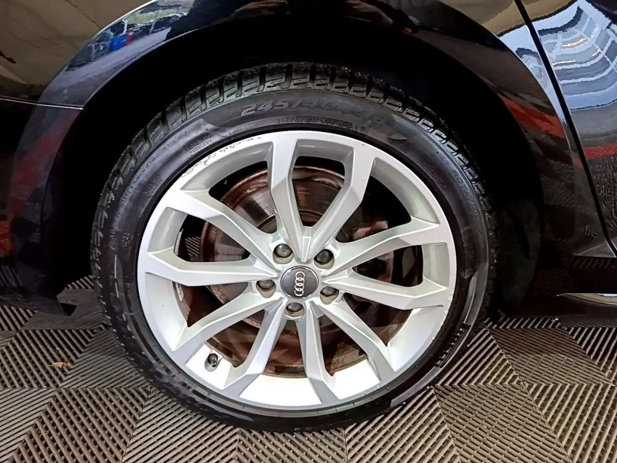 Gros plan sur la roue avant droite d’une Audi A4 noire 2018, mettant en valeur la jante alliage argentée à 10 branches.