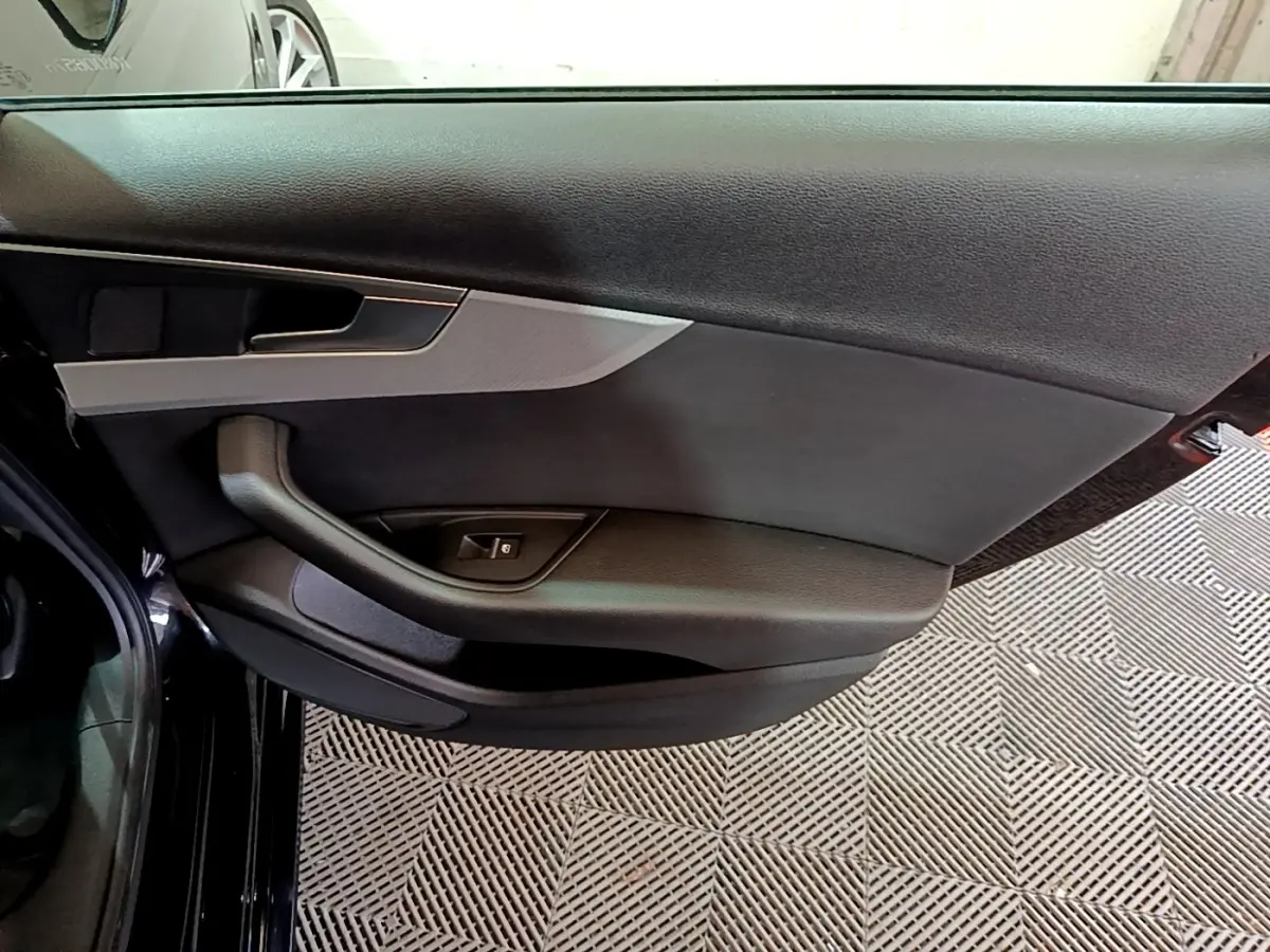 Vue rapprochée de la porte arrière gauche noire d'une Audi A4 40 TDI 2018, avec poignée et commande de vitre.