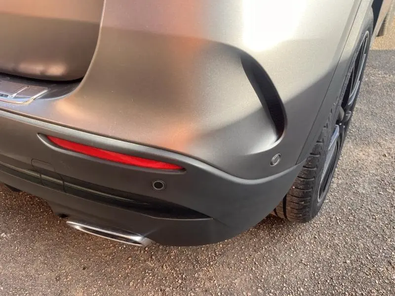 Gros plan sur le coin arrière droit gris mat du Mercedes GLA 200 d AMG Line avec sortie d’échappement chromée et feu rouge.