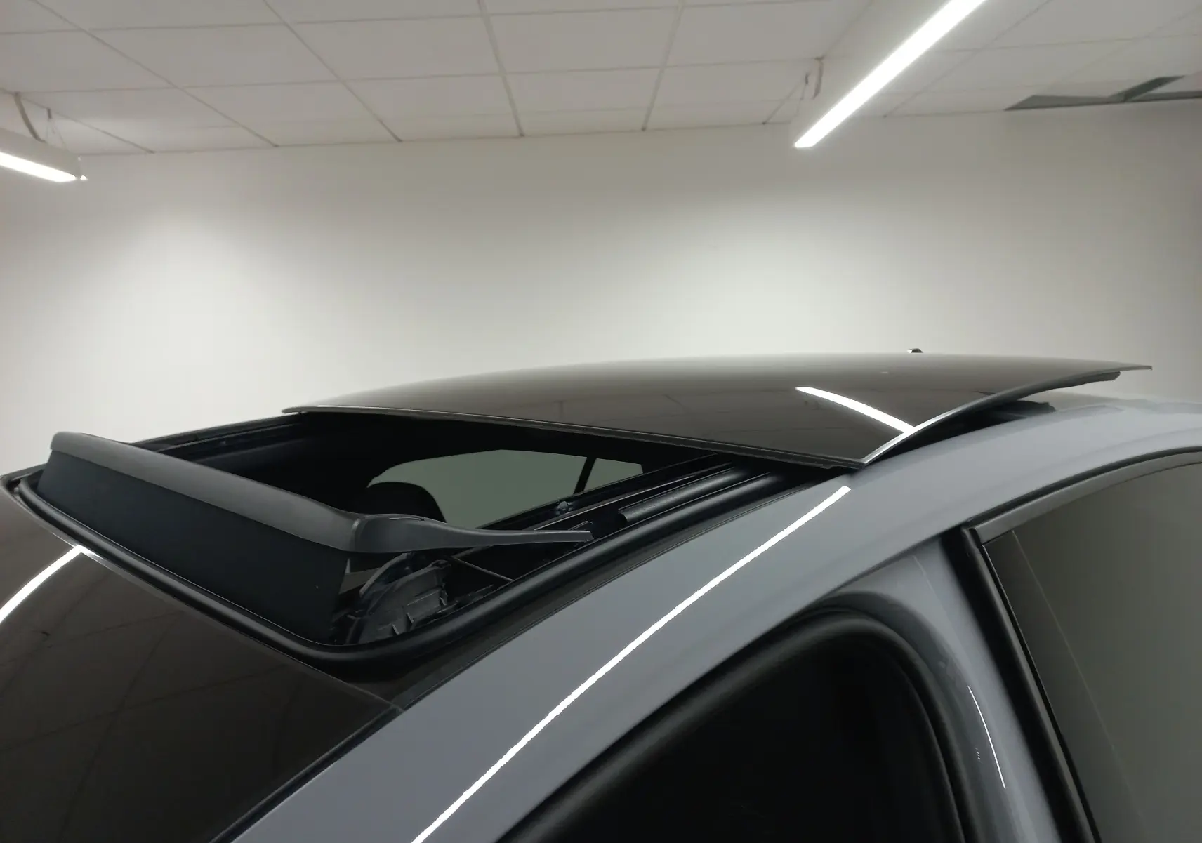 Toit ouvrant panoramique ouvert vu en gros plan sur le côté gauche d'une Volkswagen Golf gris lunaire.