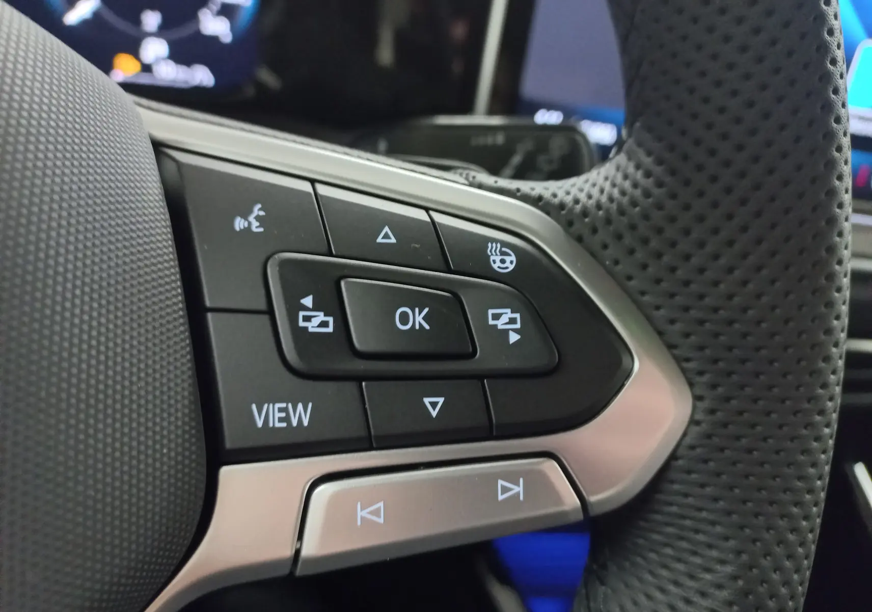 Gros plan sur les commandes multifonctions du volant cuir perforé de la Volkswagen Golf 2.0 TDI gris lunaire.