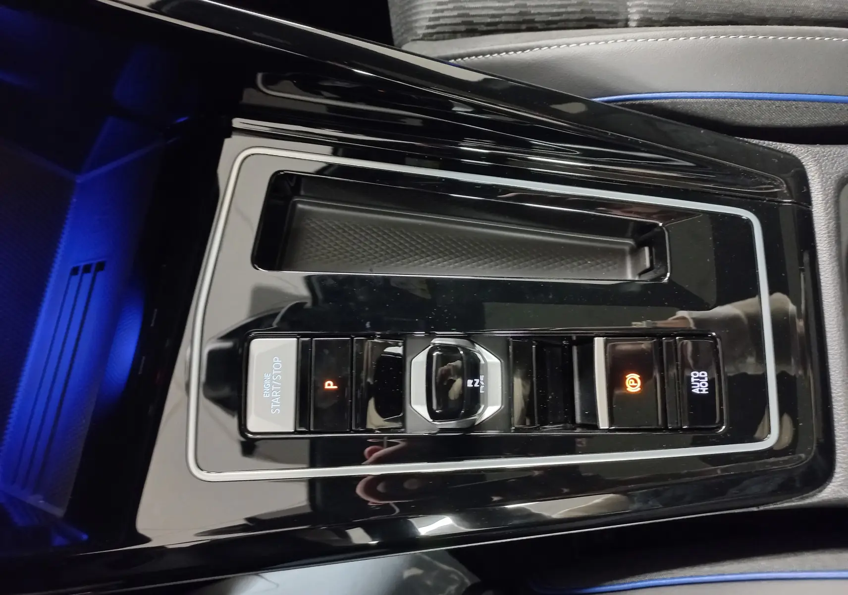 Vue rapprochée de la console centrale noire brillante de la Volkswagen Golf 2.0 TDI 150 DSG7 R-Line avec commandes de boîte auto.