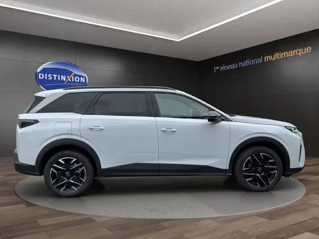 Vue latérale droite du Peugeot 5008 Nouveau blanc Okenite avec jantes alliage noires et toit contrasté noir dans un showroom.