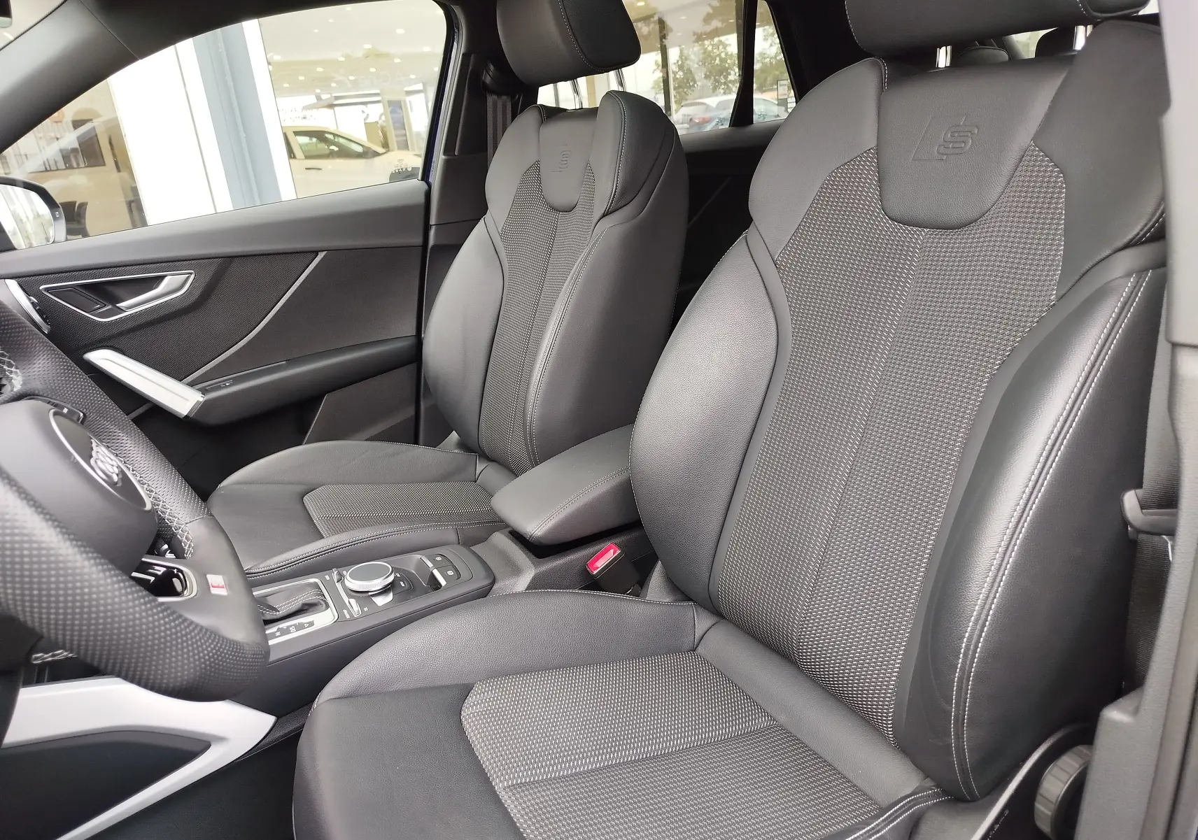 Vue intérieure côté gauche montrant les sièges avant en cuir gris avec logo S embossé sur un Audi Q2 2023.