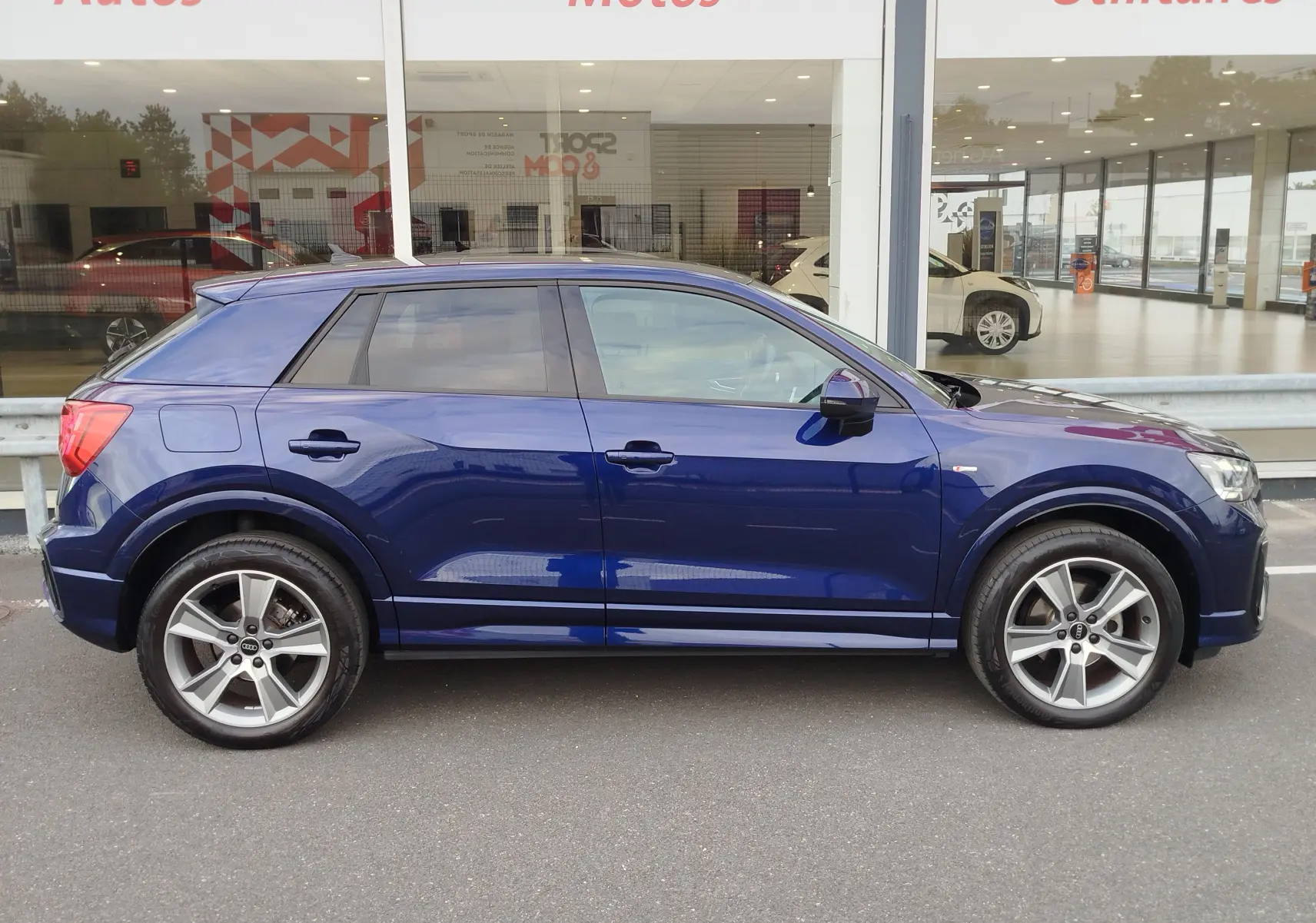 Audi Q2 bleu Navarre vue de profil côté gauche, avec jantes alliage 5 branches et finition S line visible.