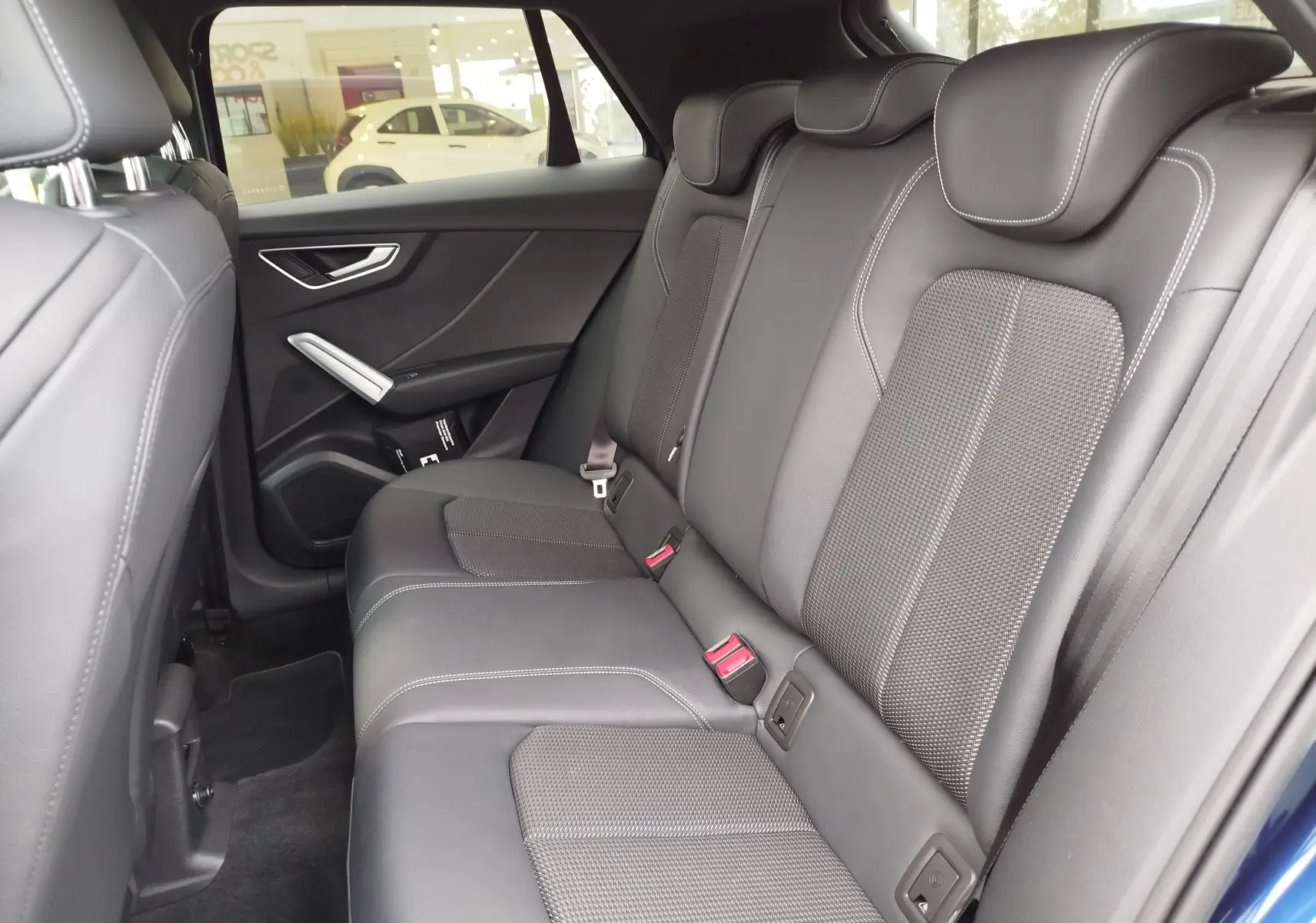 Vue intérieure arrière droite des sièges en cuir gris foncé de l'Audi Q2 35 TFSI S line 2023, avec détails de couture apparents.