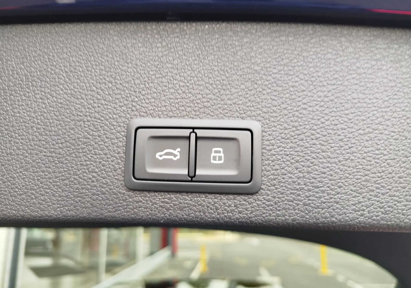 Boutons d'ouverture du coffre et de verrouillage intégrés dans la garniture intérieure du hayon d'un Audi Q2 bleu Navarre.