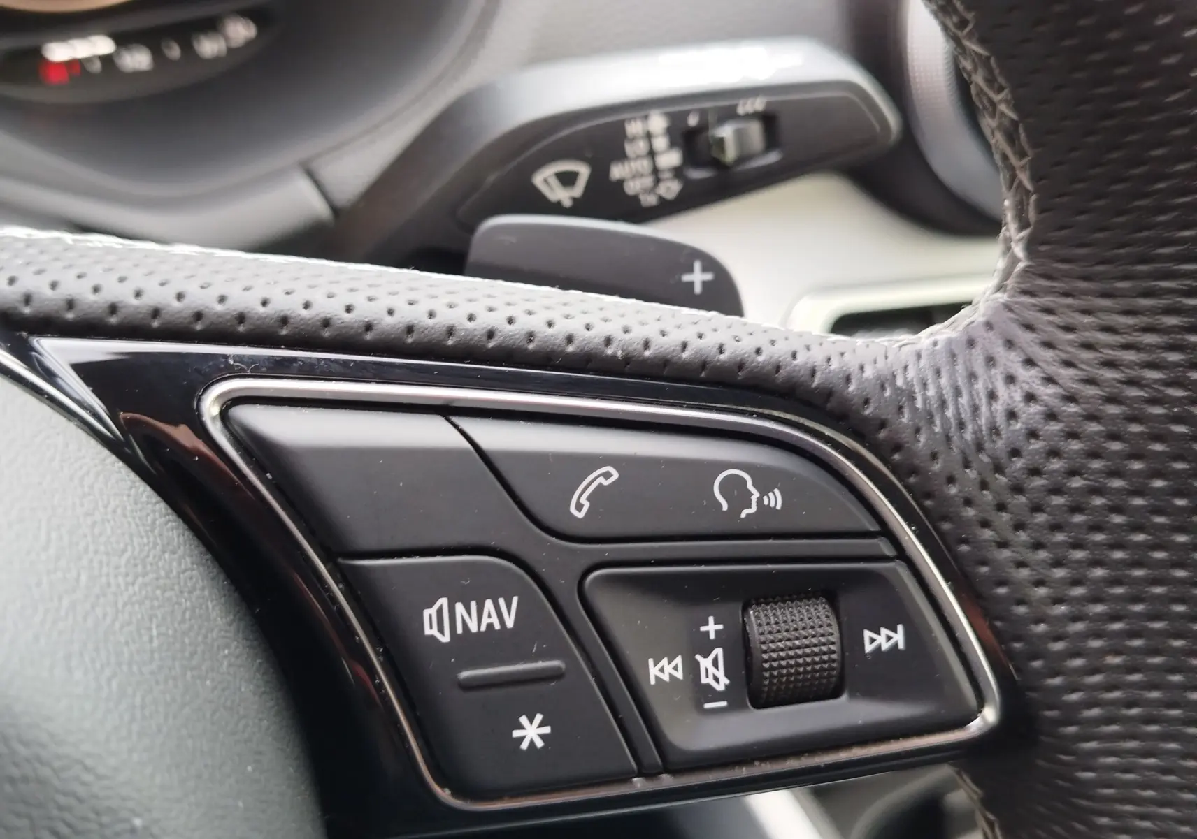 Gros plan sur les commandes multifonctions du volant en cuir perforé d'un Audi Q2 35 TFSI 2023, finition S line.
