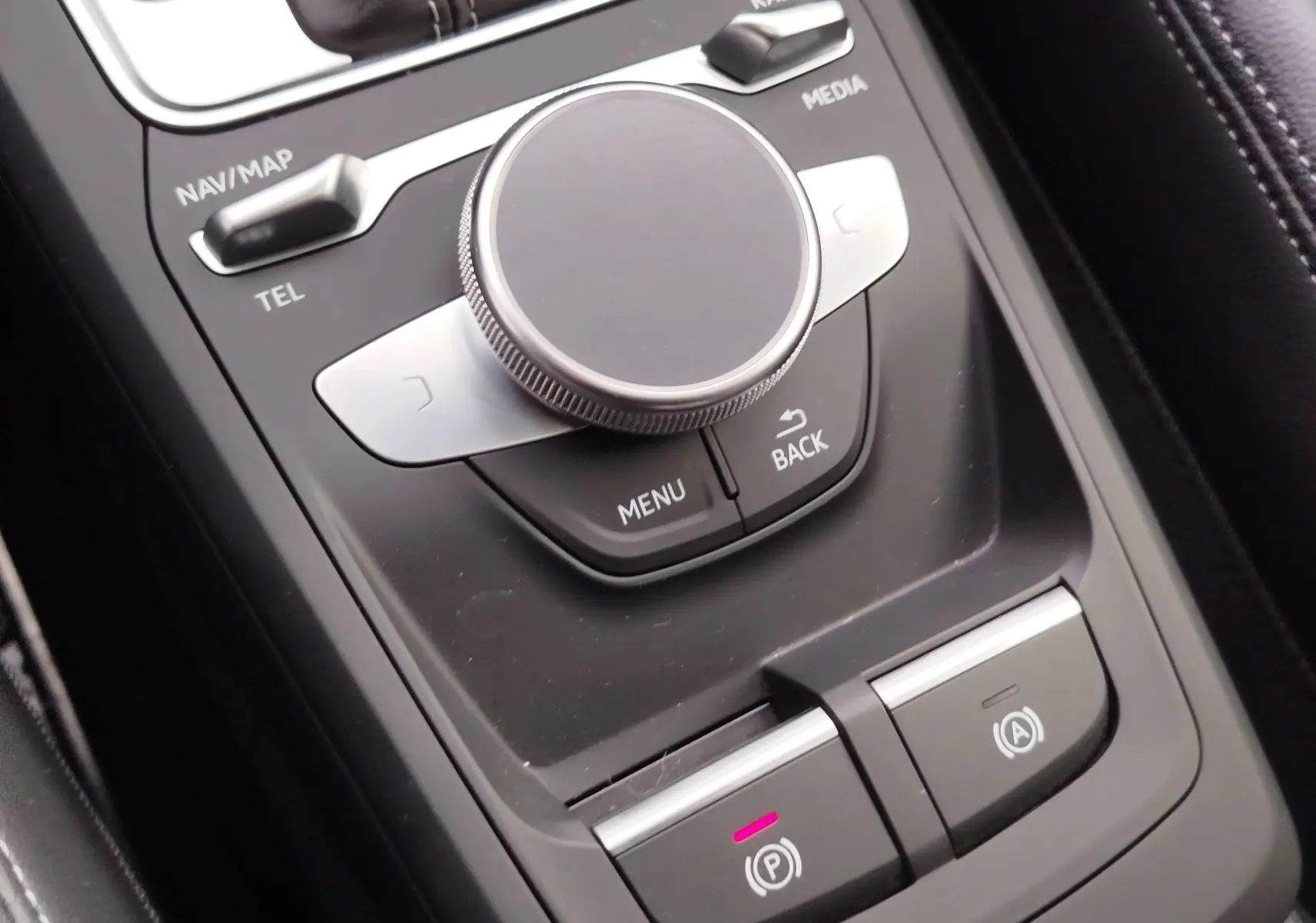 Gros plan sur la molette de commande centrale et les boutons de frein à main électrique dans l'habitacle d'un Audi Q2.