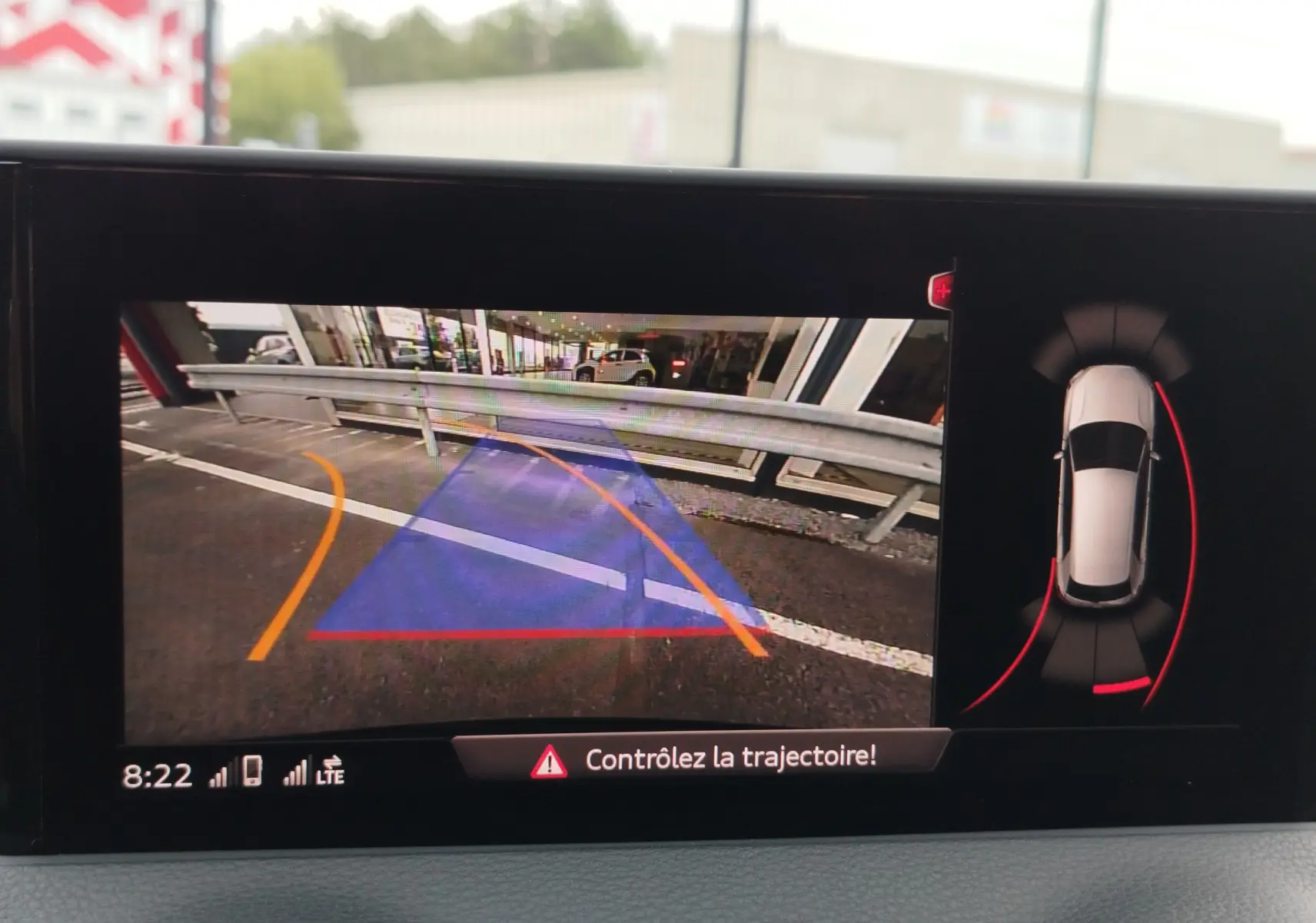 Vue de l'écran de recul de l'Audi Q2 bleu Navarre 2023, avec lignes de guidage et alertes de trajectoire.