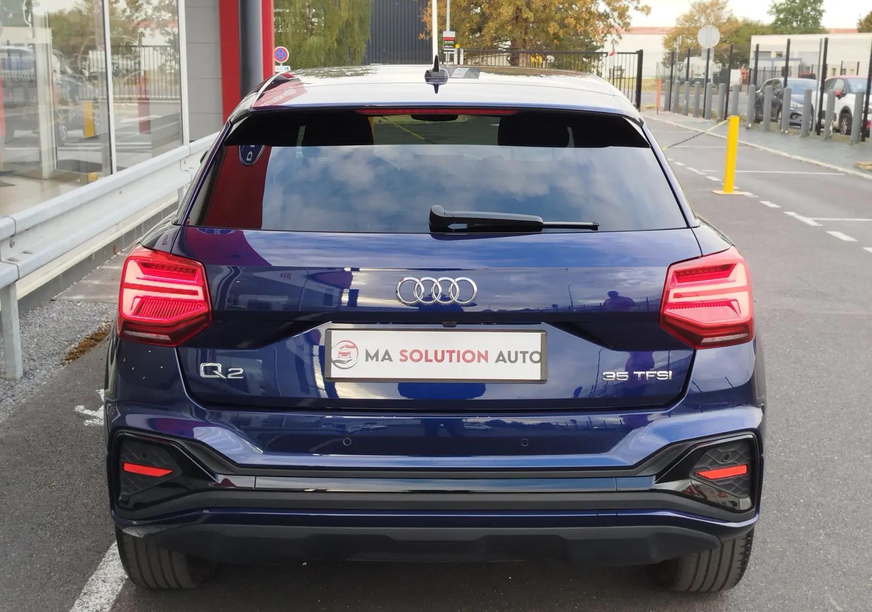 Vue arrière d'un Audi Q2 bleu Navarre 2023 avec feux LED allumés et logo 35 TFSI visible sur le hayon.
