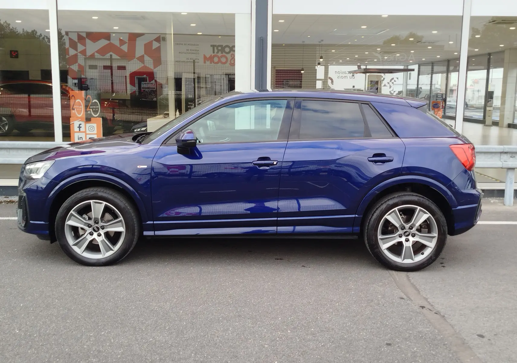 Audi Q2 bleu Navarre vue de profil côté gauche, avec jantes alliage 5 branches et toit noir contrasté.
