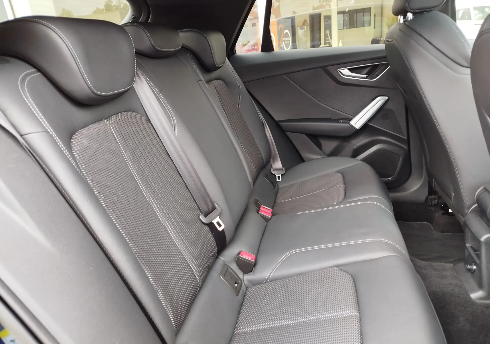 Vue latérale droite de l’habitacle arrière de l’Audi Q2 2023 avec sièges en cuir noir et surpiqûres blanches.