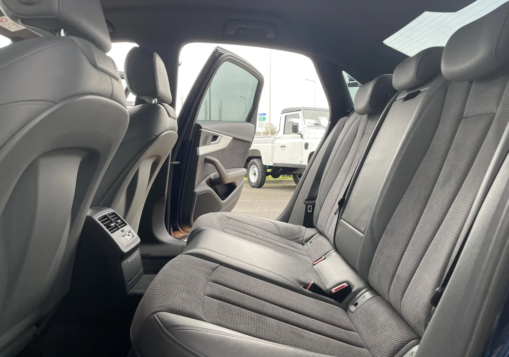 Vue intérieure arrière de l'Audi S4 2016 bleu Navarre, montrant les sièges arrière en cuir et tissu gris avec porte ouverte côté gauche.