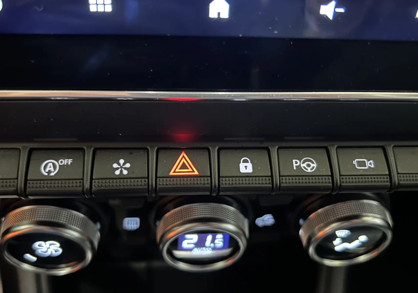 Gros plan sur la console centrale du Renault Captur 2024, boutons de sécurité et climatisation affichant 21,5°C.