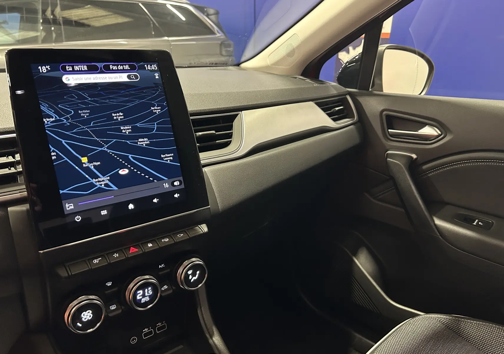 Vue intérieure côté passager du tableau de bord du Renault Captur 2024 avec écran tactile et commandes de climatisation.