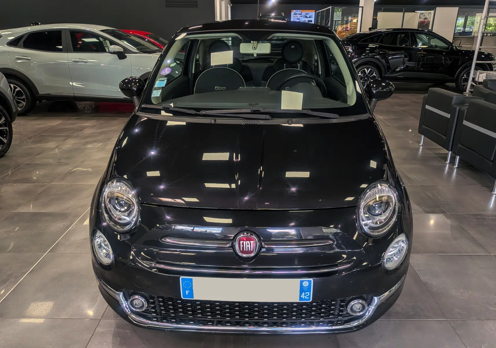 Vue frontale d'une Fiat 500 noire Crossover Black 2017 dans un showroom, avec phares ronds et logo rouge visible.