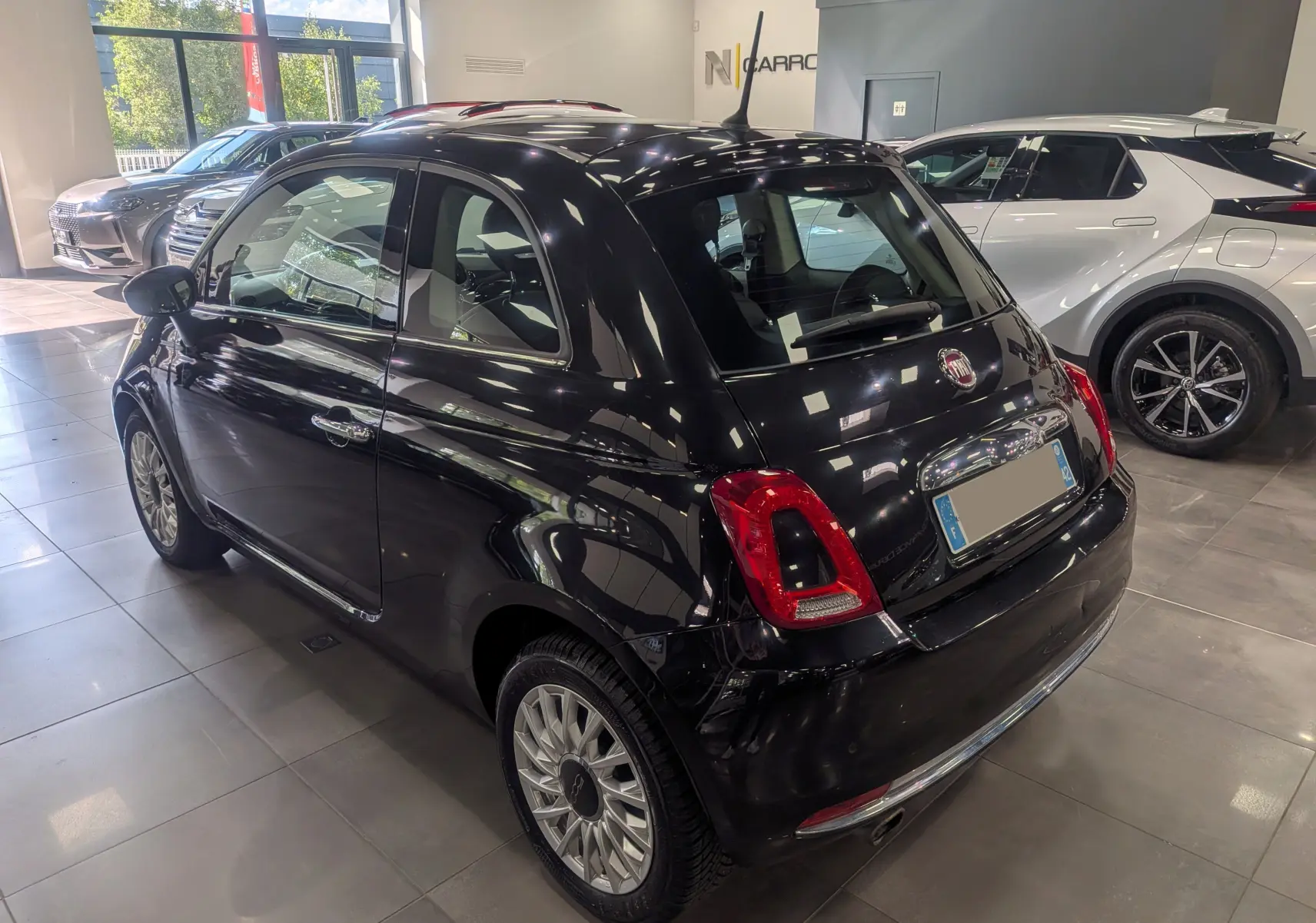 Fiat 500 1.2 69 CH Lounge noire vue en 3/4 arrière droit dans un showroom avec jantes alliage multibranches.