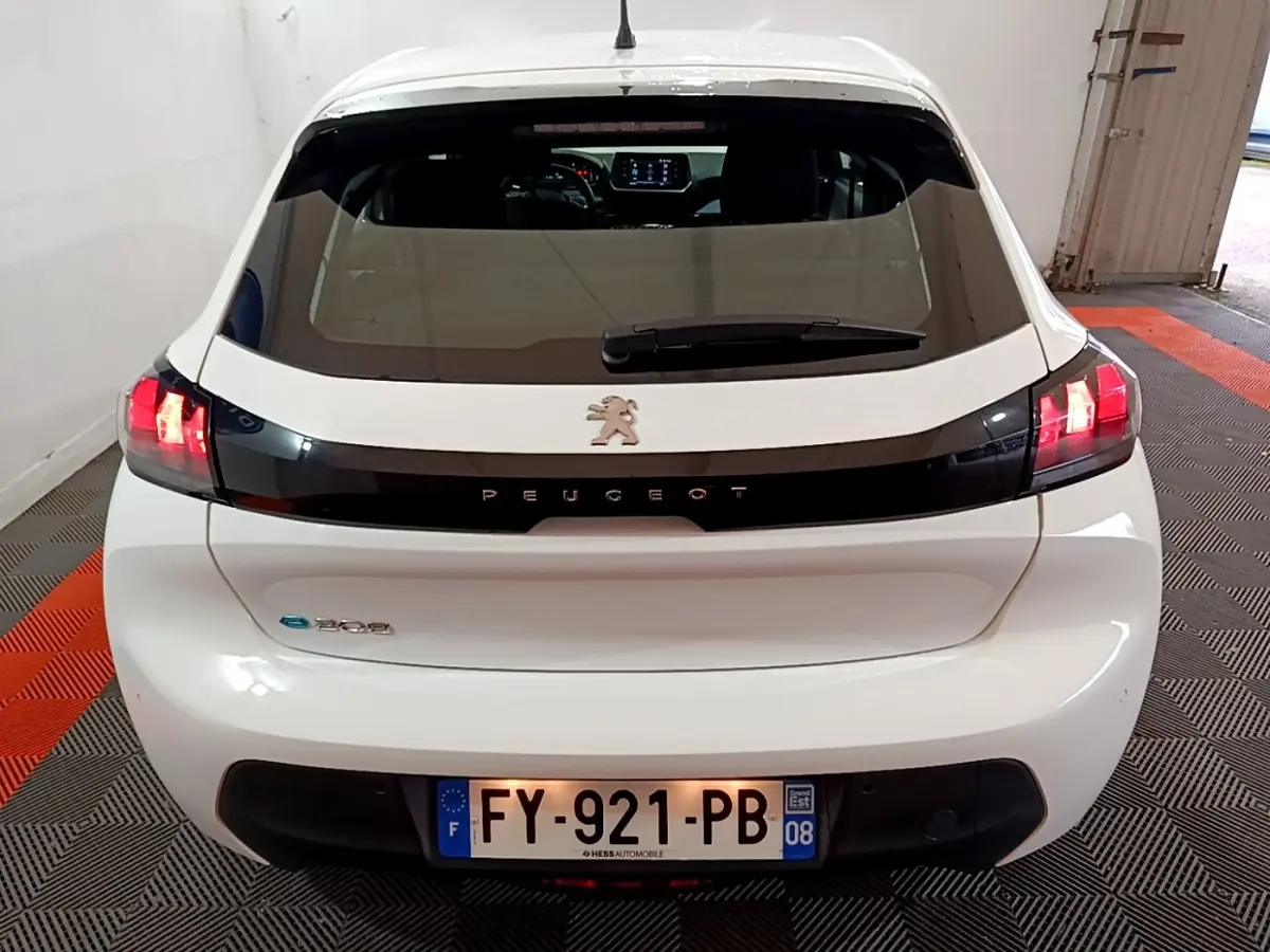 Vue arrière d'une Peugeot 208 électrique Active Business blanche avec feux LED allumés en intérieur.