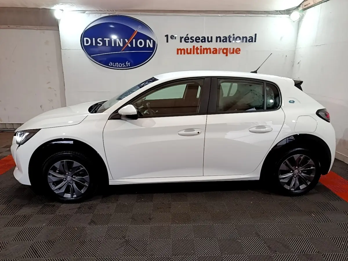 Profil côté gauche d'une Peugeot 208 électrique Active Business blanche, avec jantes alliage et badge e-208 visible à l'arrière.