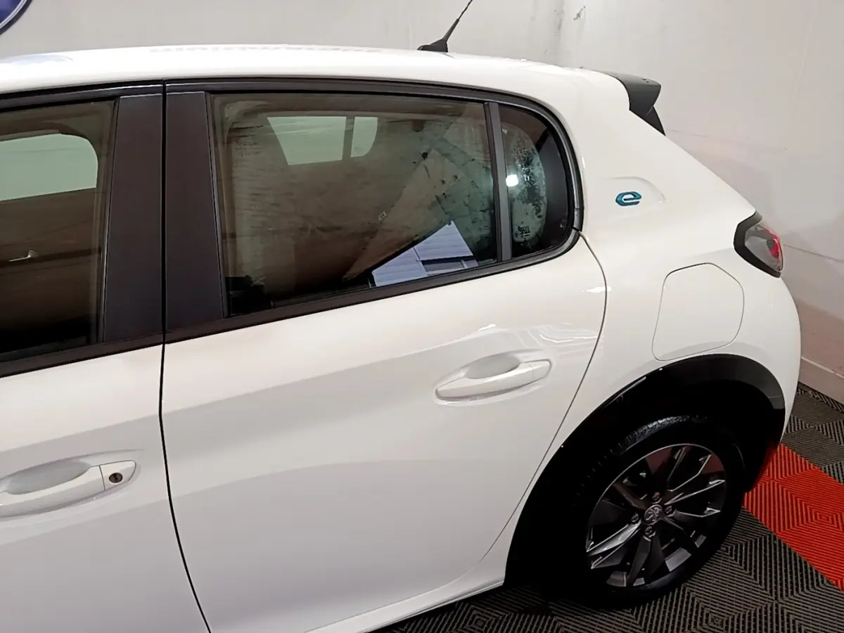 Vue côté droit arrière d'une Peugeot 208 électrique Active Business blanche avec logo "e" bleu distinctif.
