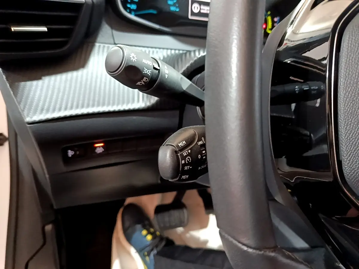 Gros plan sur le volant cuir noir et commandes au volant de la Peugeot 208 électrique Active Business 2021.