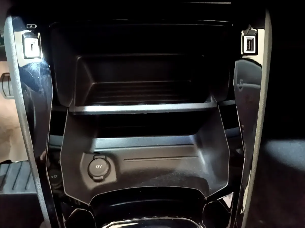 Gros plan sur la console centrale noire du Peugeot 208 Electrique Active Business 2021 avec prise 12V et ports USB.