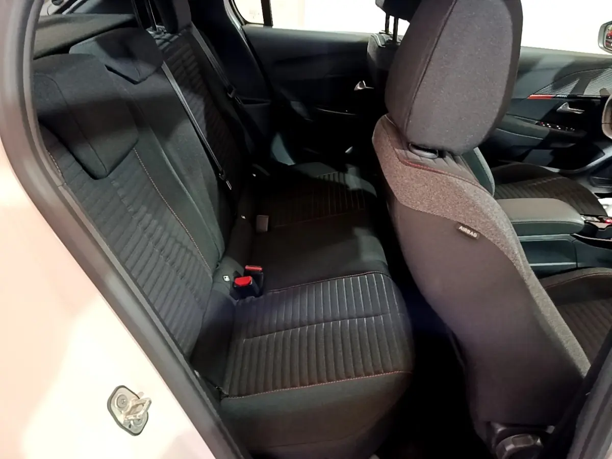 Vue intérieure côté gauche de la banquette arrière noire avec surpiqûres rouges d'une Peugeot 208 blanche Electrique Active Business 2021.