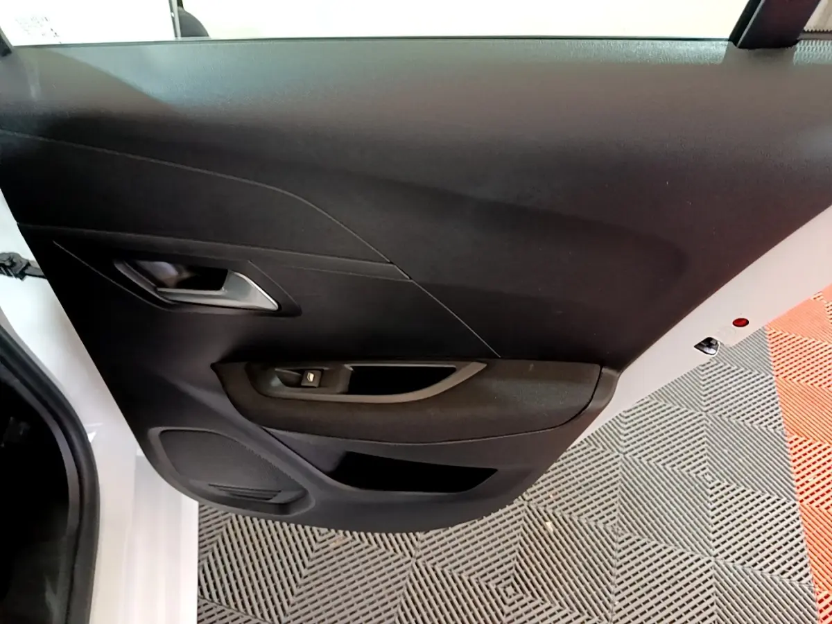 Vue rapprochée de la porte côté gauche blanche du Peugeot 208 Electrique Active Business avec panneau noir et commande de vitre.