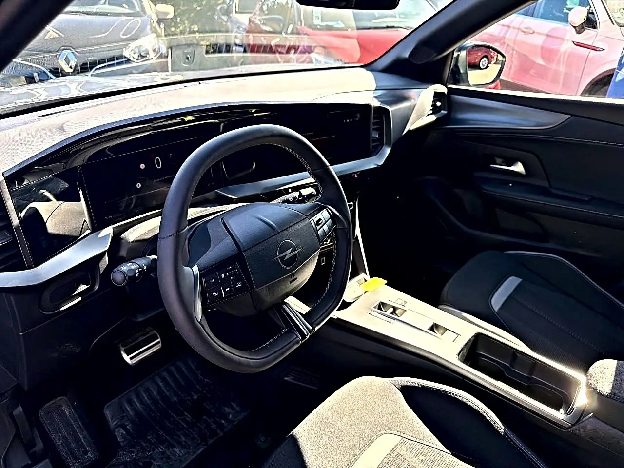 Vue intérieure côté conducteur de l'Opel Mokka Electric gris, volant multifonction et tableau de bord numérique moderne.