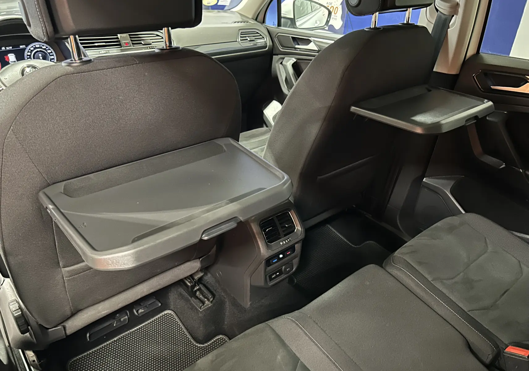 Vue intérieure arrière du Volkswagen Tiguan Allspace 2018 avec tablettes rabattables sur les dossiers des sièges avant.