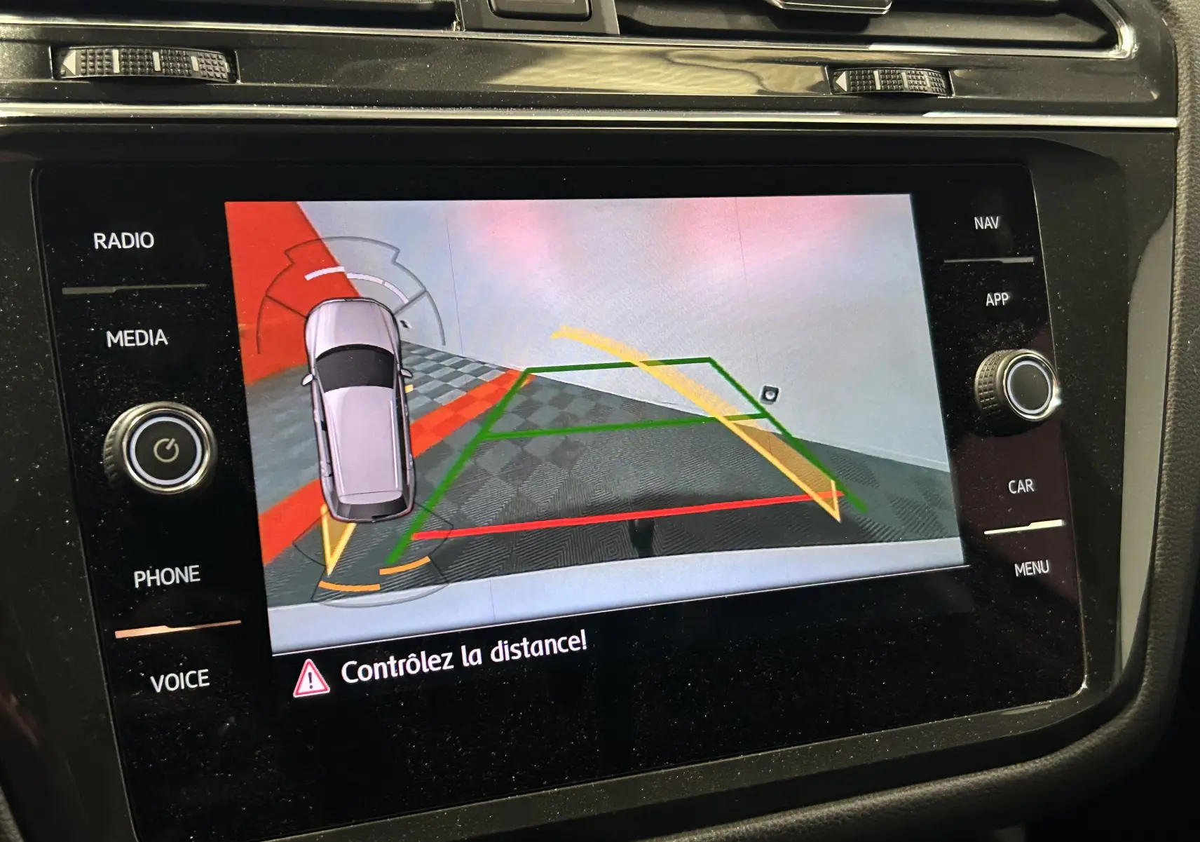 Affichage de la caméra de recul du Volkswagen Tiguan Allspace blanc avec lignes de guidage colorées sur l'écran central.