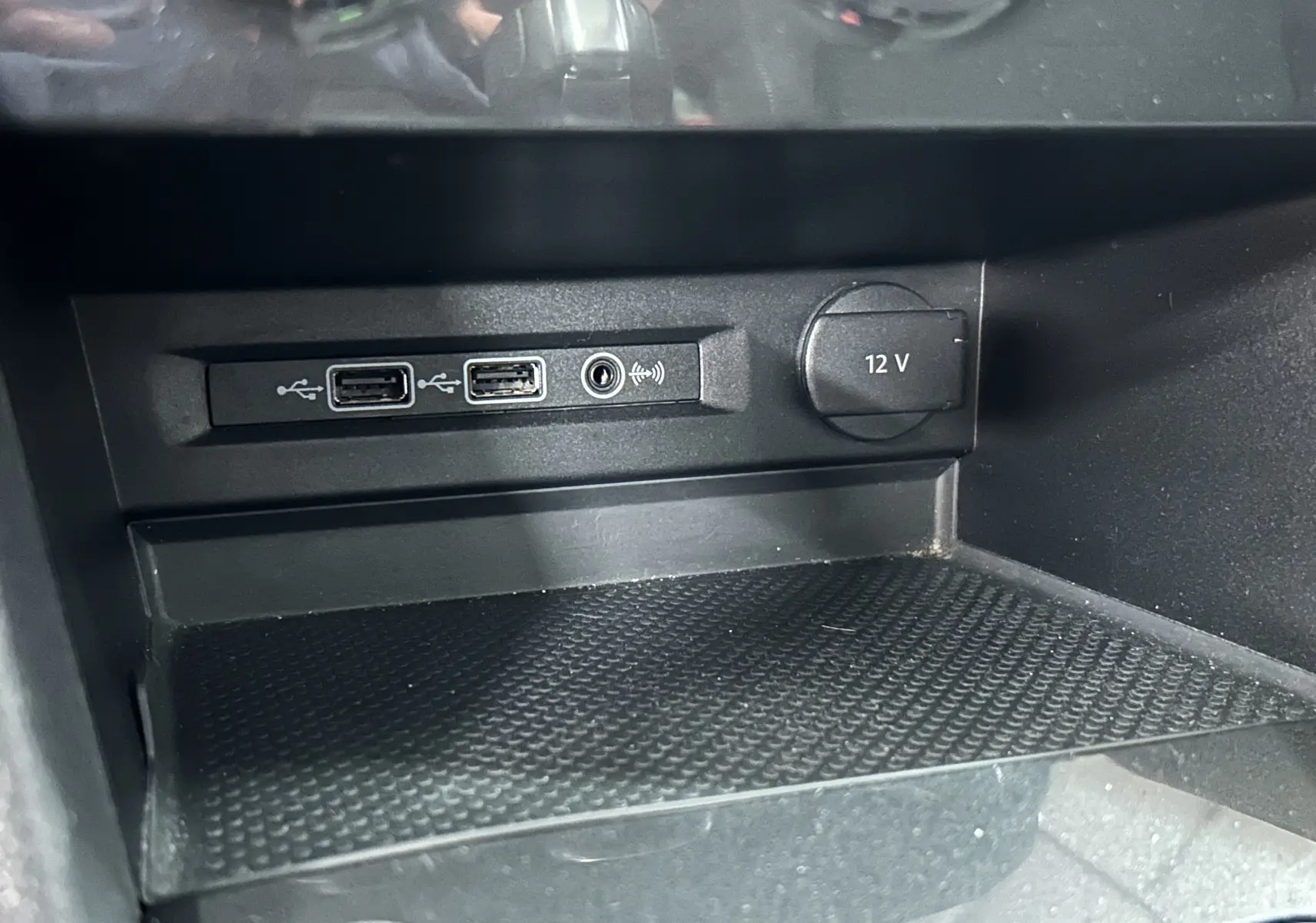 Prise 12V et ports USB visibles dans la console centrale d'un Volkswagen Tiguan Allspace blanc, vue rapprochée intérieure.
