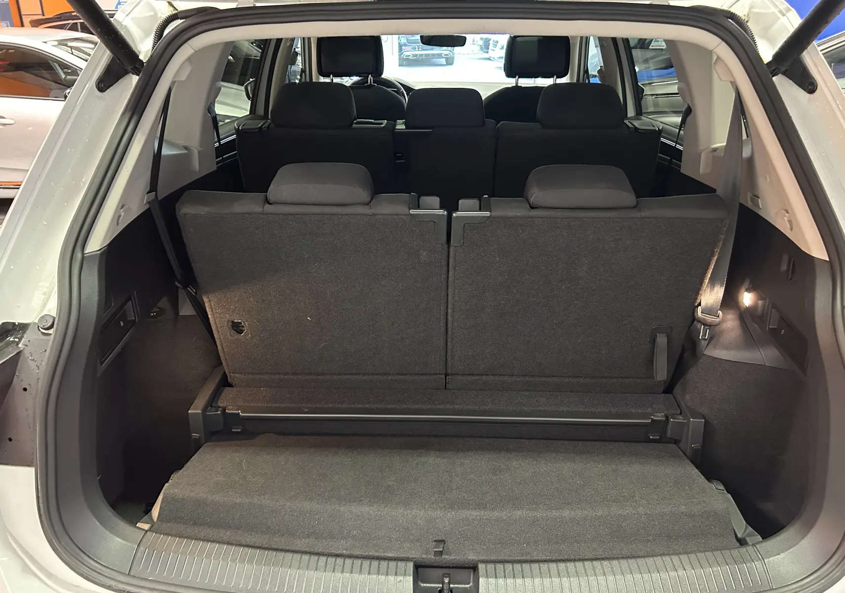 Vue arrière du coffre ouvert du Volkswagen Tiguan Allspace blanc, montrant les sièges arrière en position verticale.